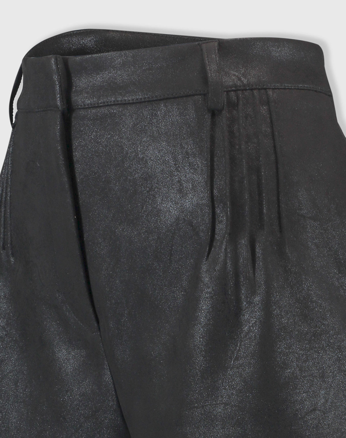 Detalhe em close do tecido suedine com acabamento metalizado do shorts preto, evidenciando textura e costuras