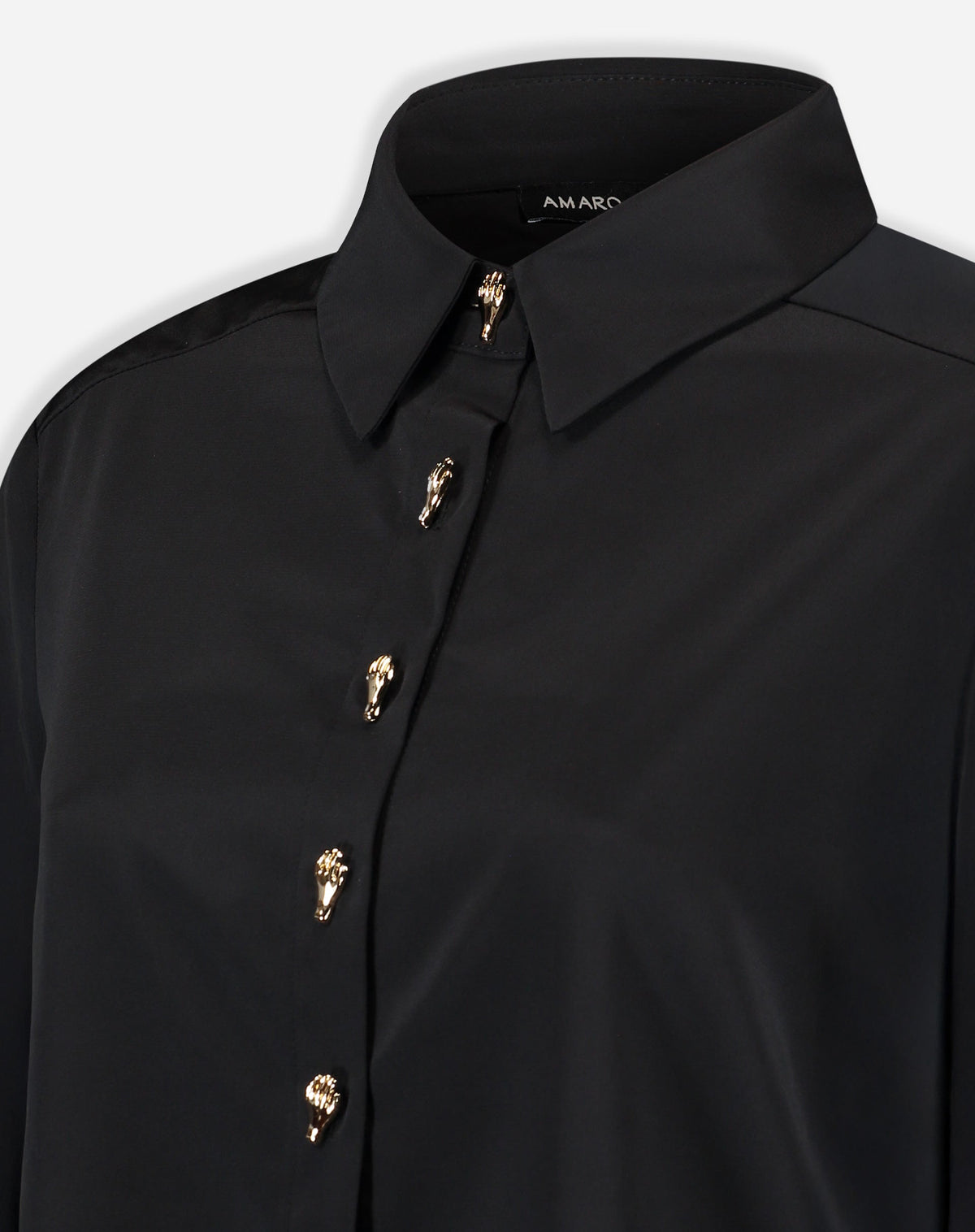 Close-up do colarinho pontudo e parte superior da camisa preta mostrando o acabamento da gola e o primeiro botão dourado