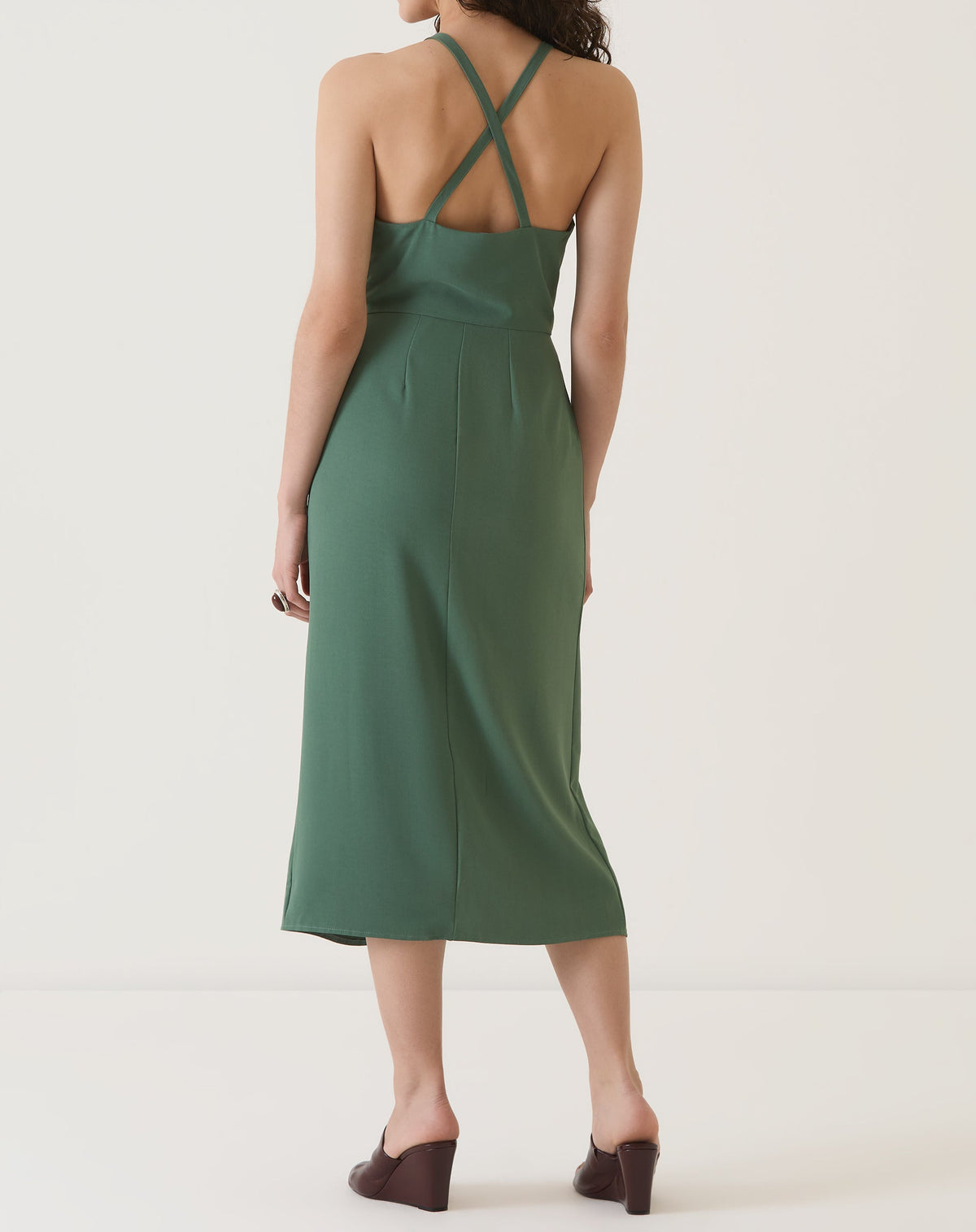 Vista traseira do vestido verde com alças cruzadas e comprimento midi.
