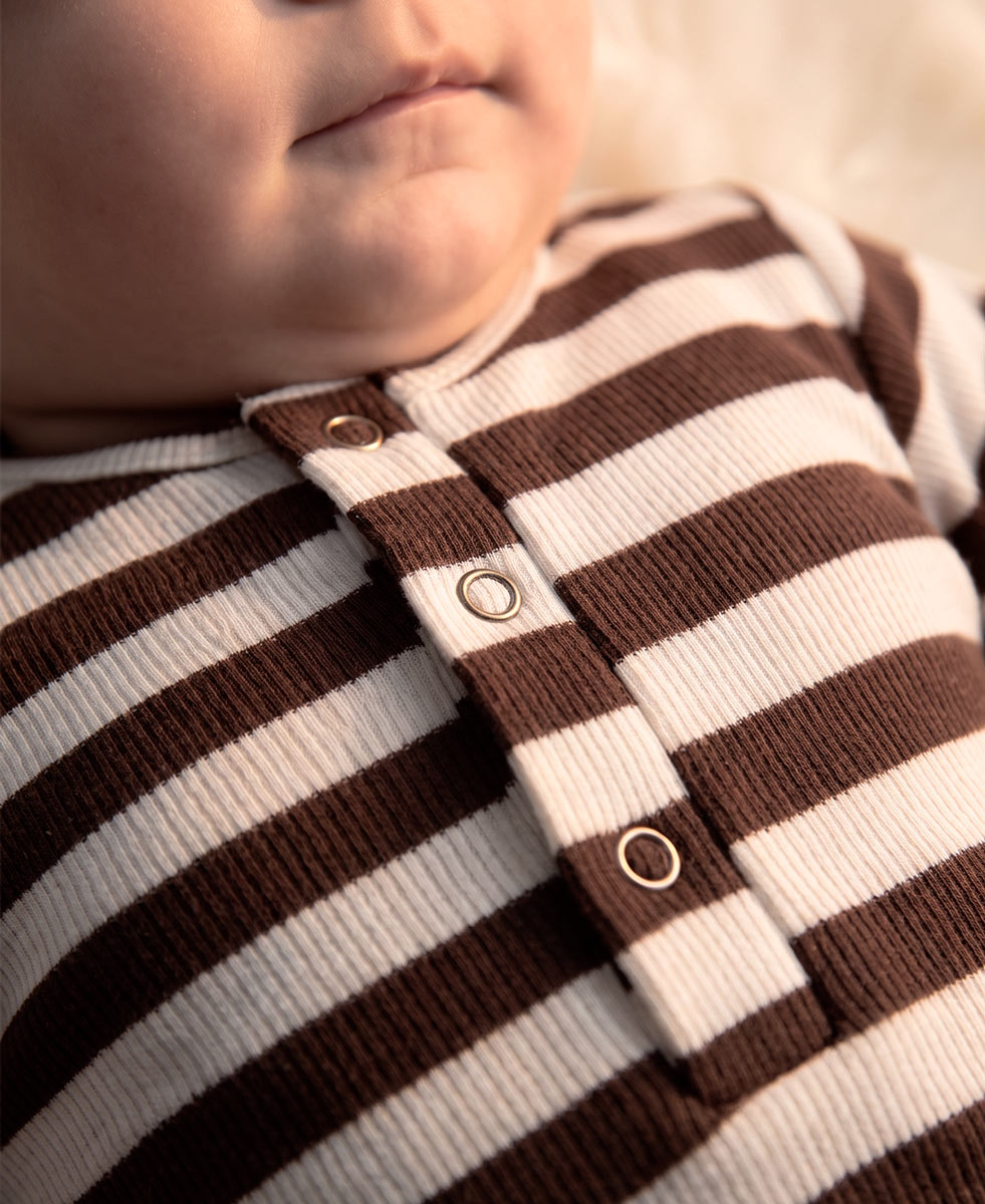 Conjunto Body + Calça Canelada Bebê Listras Marrom MiniMalista Baby — pose lifestyle do bebê no aconchego do inverno, algodão canelado 100% respirável antialérgico, escala granular do RN aos 18-24 meses.