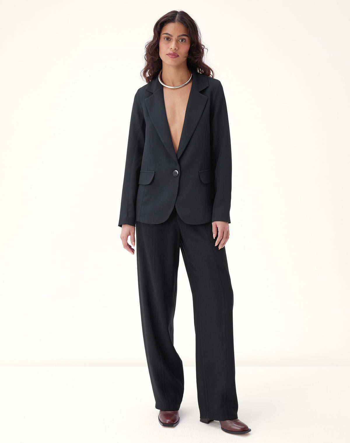 Modelo vestindo blazer preto com calça preta, mostrando o visual completo.