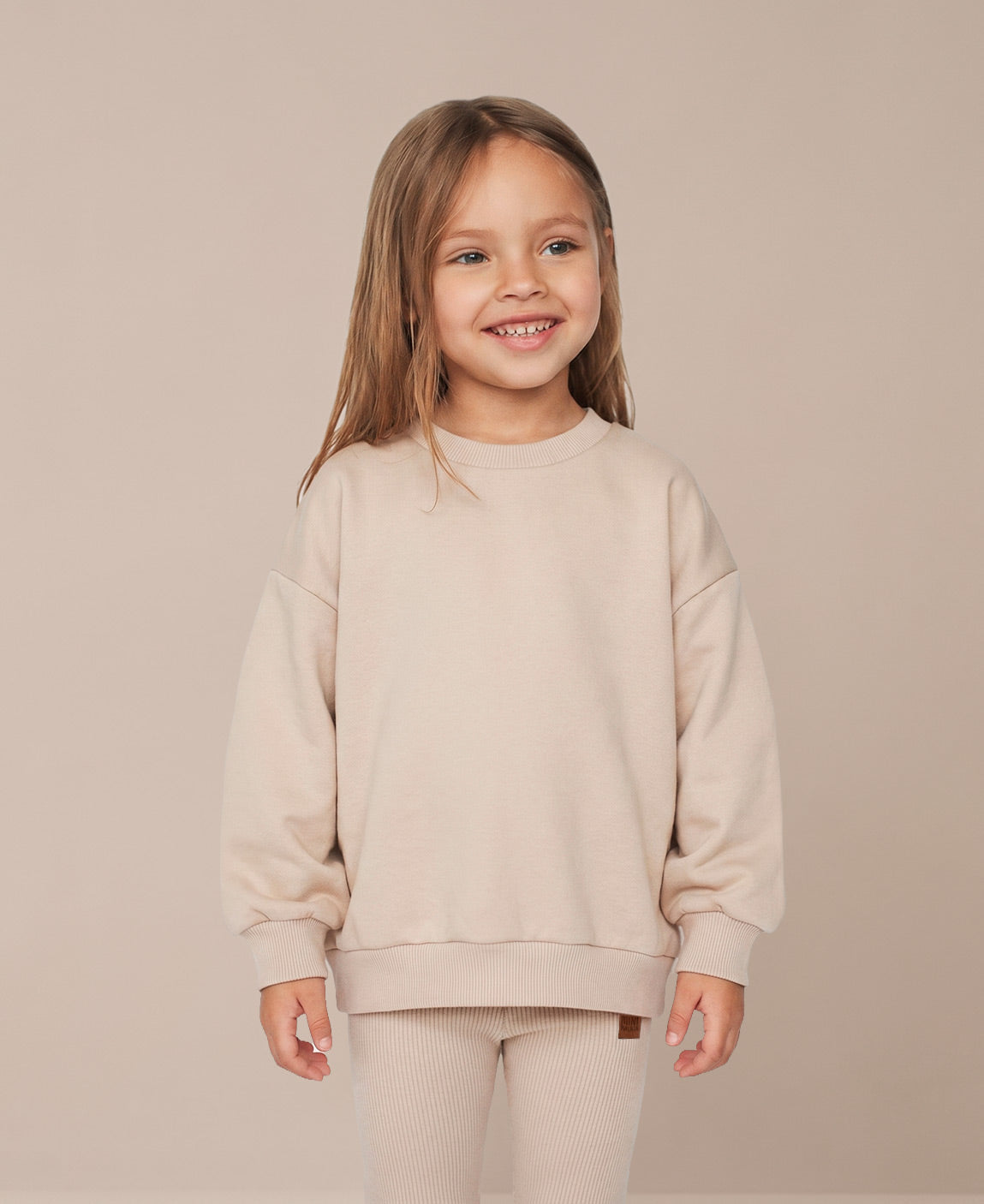 MiniMalista Conjunto Moletom + Calça Canelada Liso Bege Claro vista costas. Moletom oversized soltinho + calça canelada slim, look infantil monocromático unissex, estética escandinava minimalista para bebê e criança, cor neutra acolhedora.