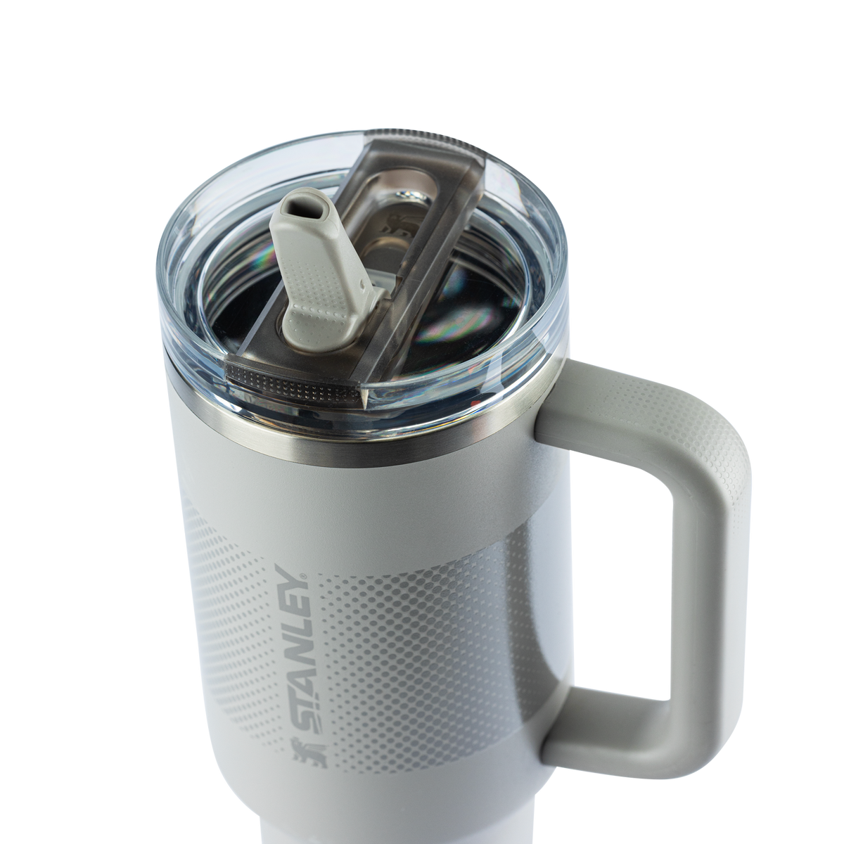 
Caneca térmica cinza claro da marca Stanley, com alça integrada e tampa removível com bico. Possui padrão texturizado e o logotipo "STANLEY" gravado.